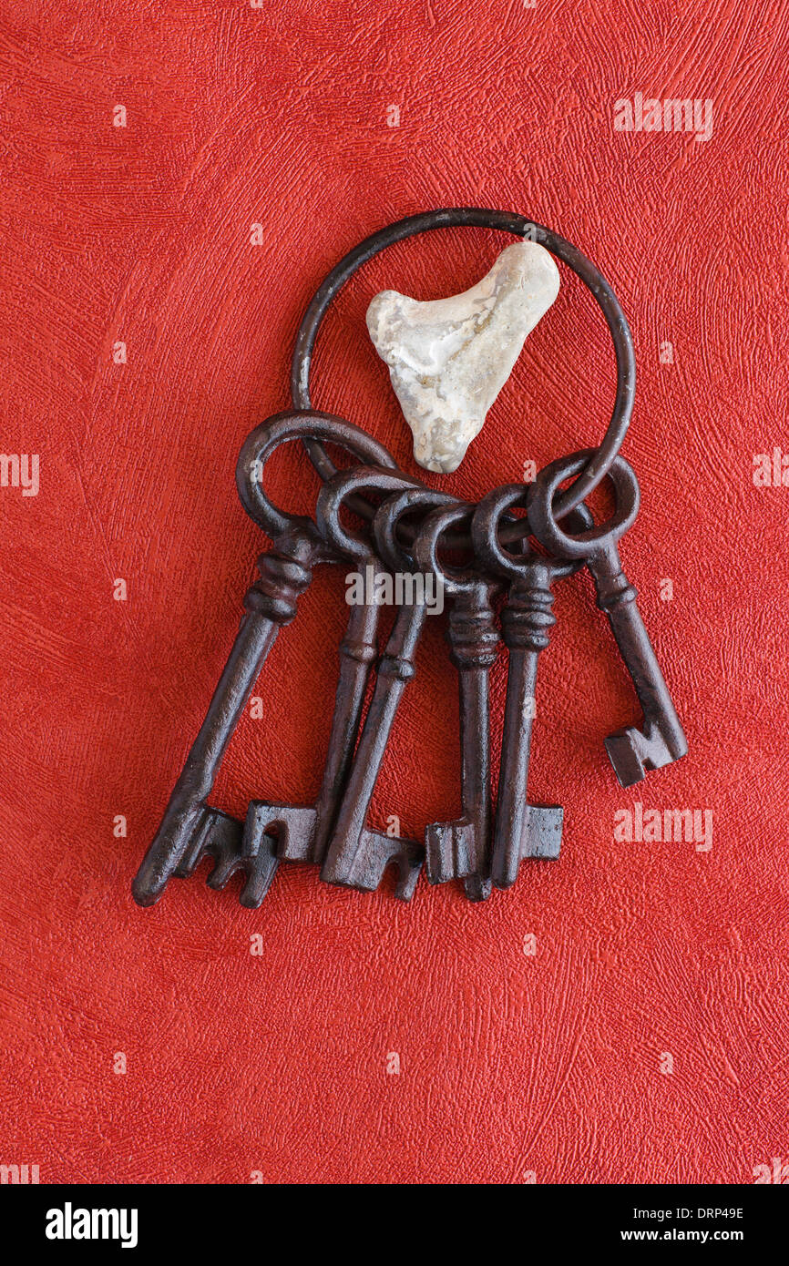 Vecchio mazzo di chiavi su uno sfondo di colore rosso, il cuore di pietra Foto Stock