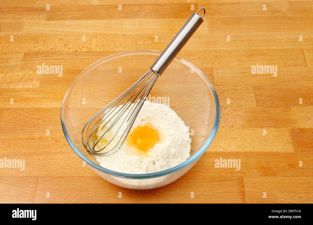 Torte con un uovo e una frusta in una ciotola di vetro su una cucina in legno piano di lavoro Foto Stock