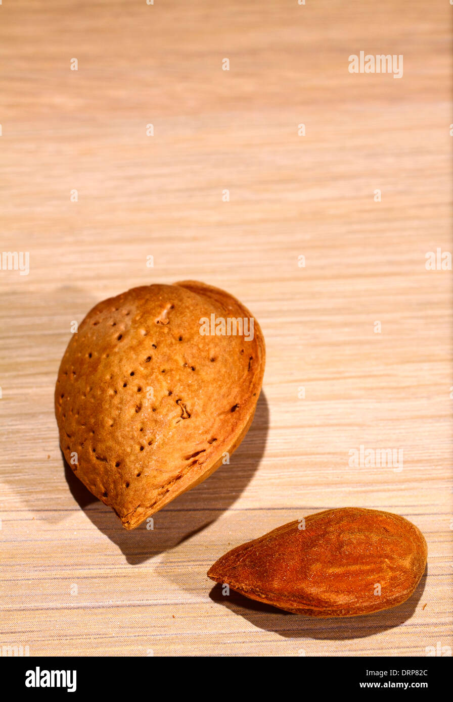 Dado di mandorla al di fuori del guscio su effetto legno sfondo con spazio per la copia Foto Stock