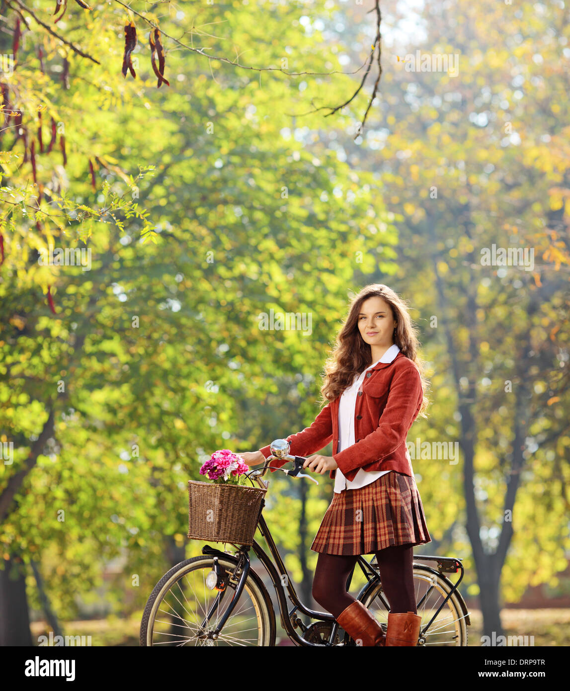 Bellissima femmina che pongono in un parco con la sua bicicletta Foto Stock