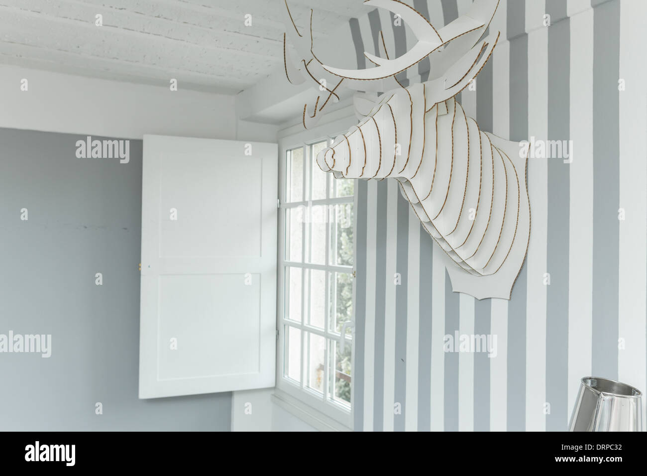 Decorativo testa di cervo sulla parete ricoperta di carta da parati a strisce. Foto Stock