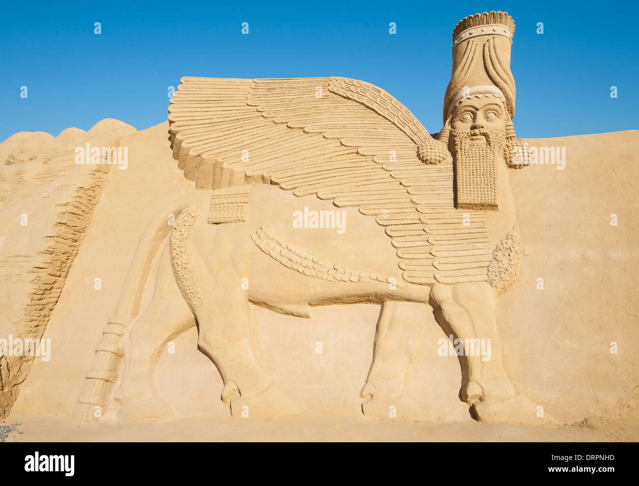 Grande la scultura di sabbia statua della divinità Lamassu a sand city theme park contro un cielo blu sullo sfondo Foto Stock