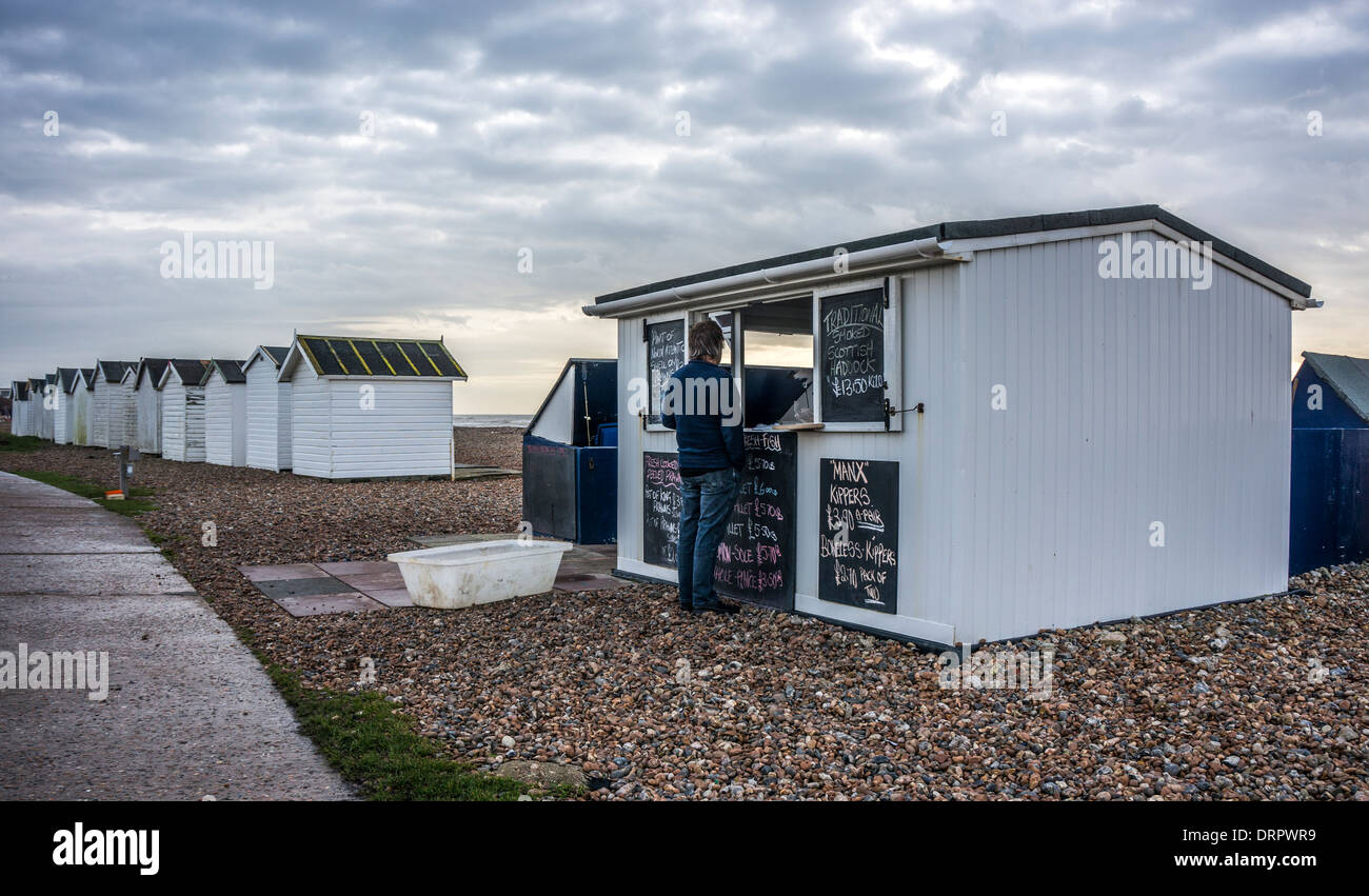 L'uomo acquistare localmente il pesce pescato dal venditore della capanna sulla Goring-da-mare spiaggia ghiaiosa, vicino a Worthing West Sussex, in Inghilterra, Regno Unito. Foto Stock