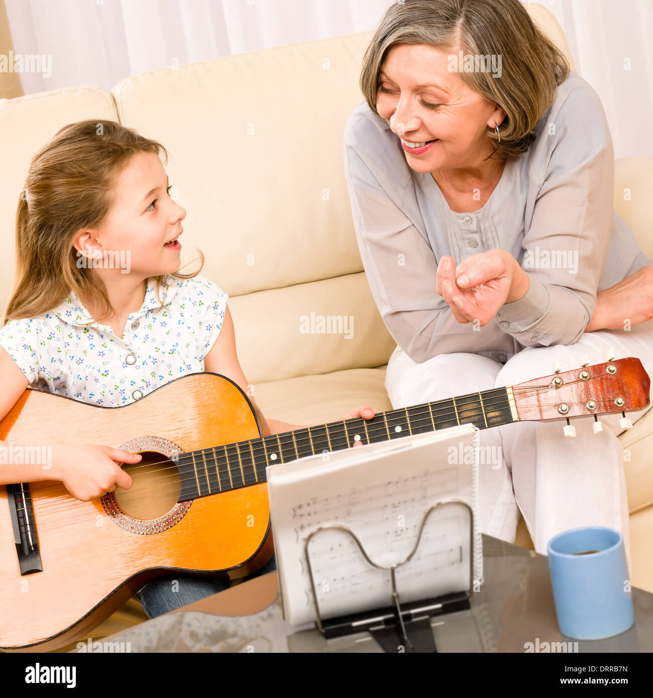 Ragazza giovane cantare suonare la chitarra alla nonna Foto Stock