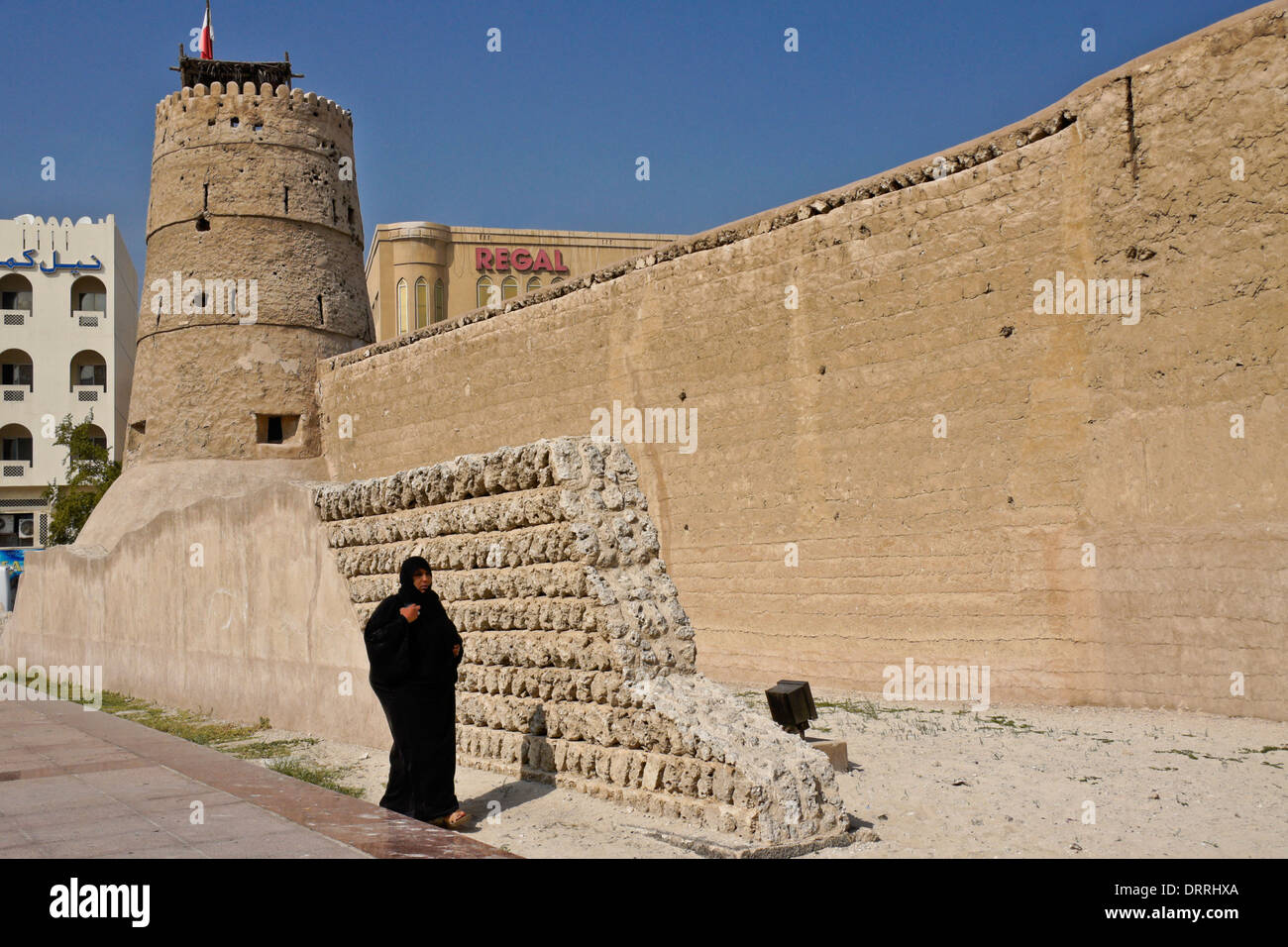 Donna musulmana a piedi di pareti esterne di Al-Fahdi Fort, Vecchio di Dubai, Emirati Arabi Uniti Foto Stock