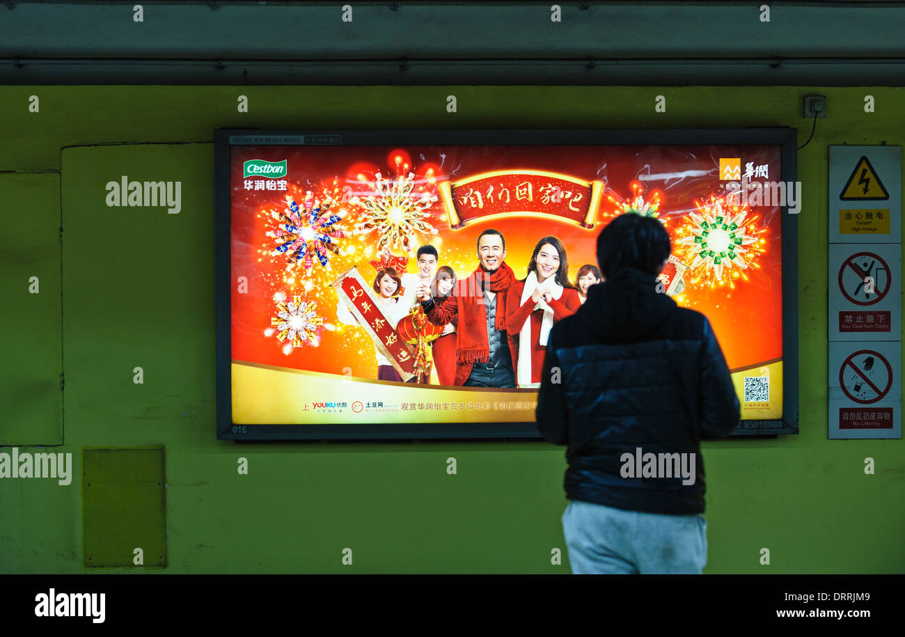 Uomo in attesa per la metropolitana di fronte a una pubblicità di schermo a LED. La metropolitana di Pechino, Cina. Foto Stock