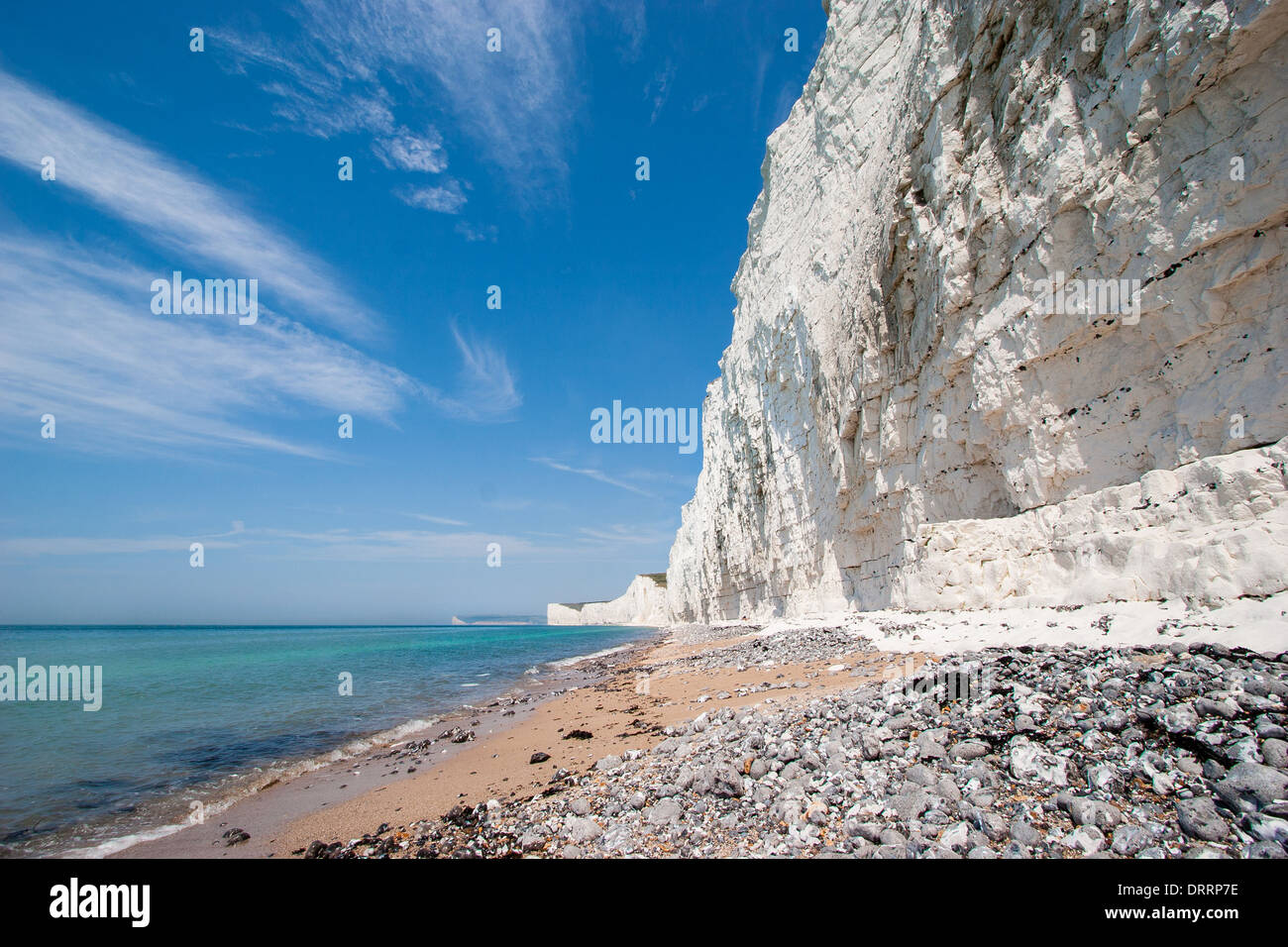Di ghiaia e sabbia spiaggia sottostante bianco gesso scogliere delle Sette sorelle in East Sussex Regno Unito Foto Stock