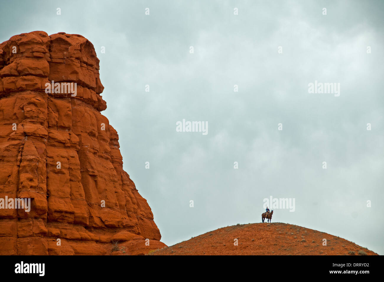 Un lone cowboy a cavallo sorge sulla sommità di una collinetta alta nel camino Rock area del Bighorn Mountains in Wyoming Foto Stock