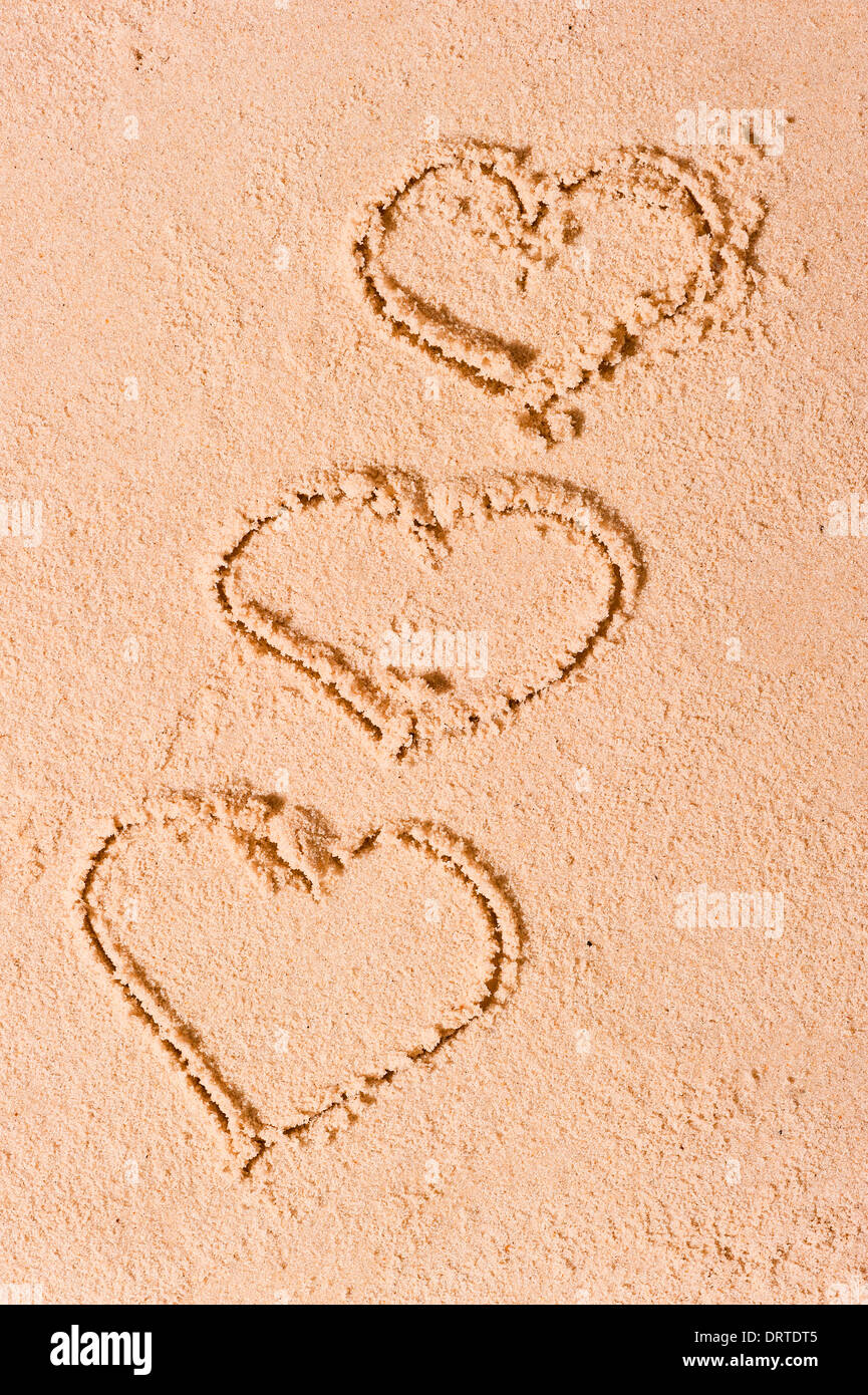 Tre cuori attirato sulla sabbia bagnata Foto Stock