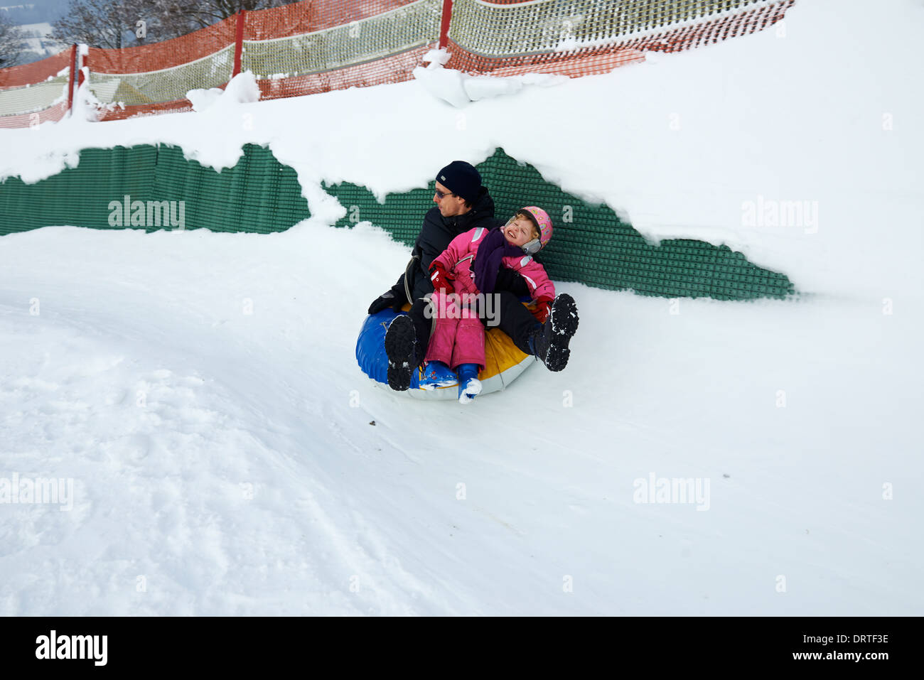 Padre e figlia avendo divertimento nella neve tubo interno - snowtubing Foto Stock