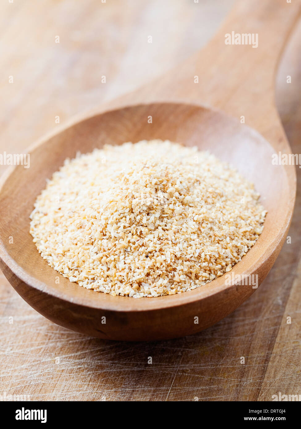 Aglio tritato in un cucchiaio di legno in composizione verticale Foto Stock