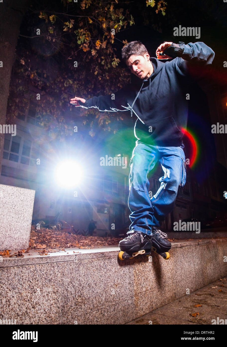 Giovane uomo rollerskating praticanti. Il giovane è rettificare un cordolo. Foto Stock