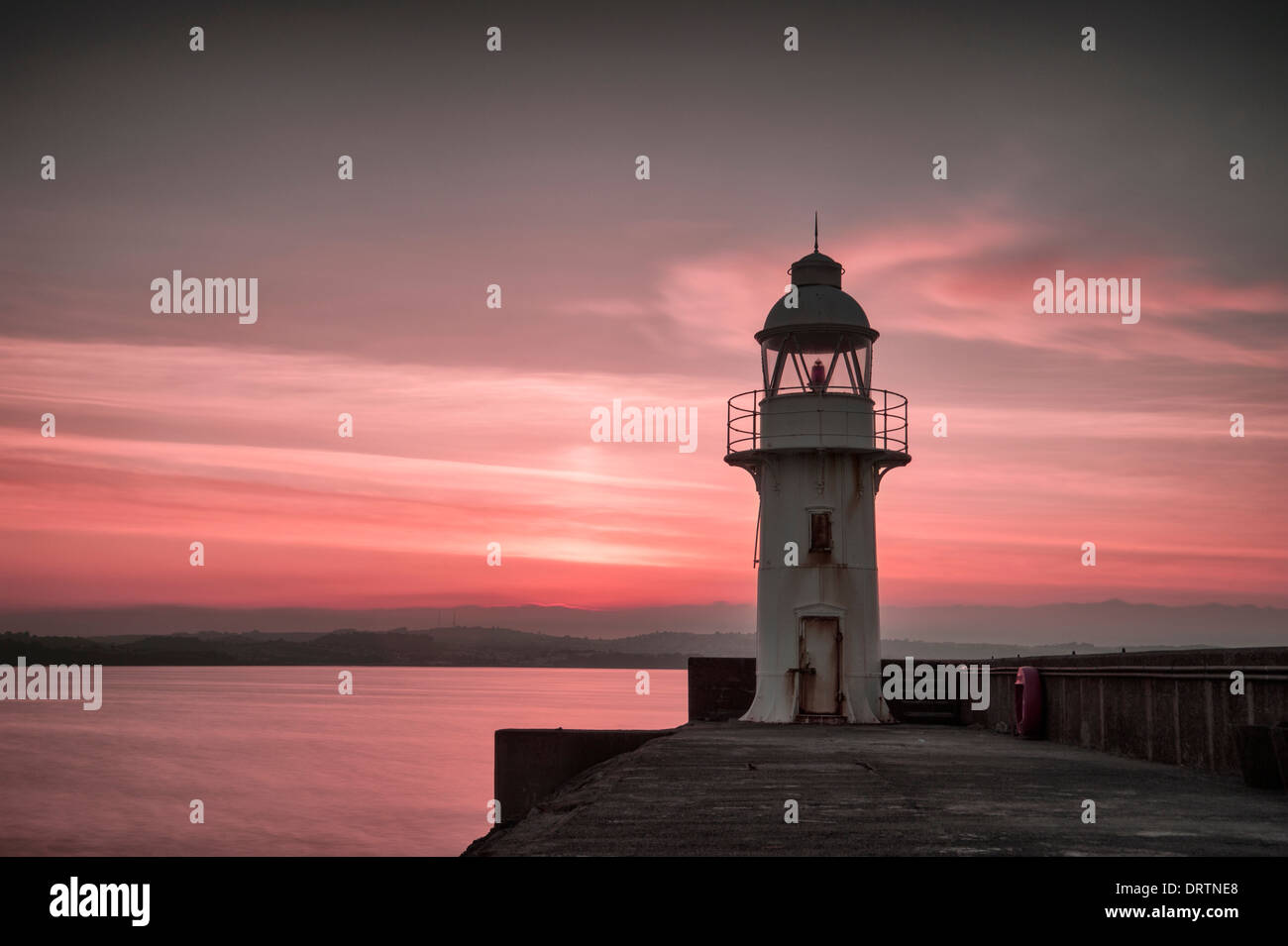 Faro e frangiflutti nella pesca costiera porto di Brixham Devon meridionale presi al tramonto. Foto Stock
