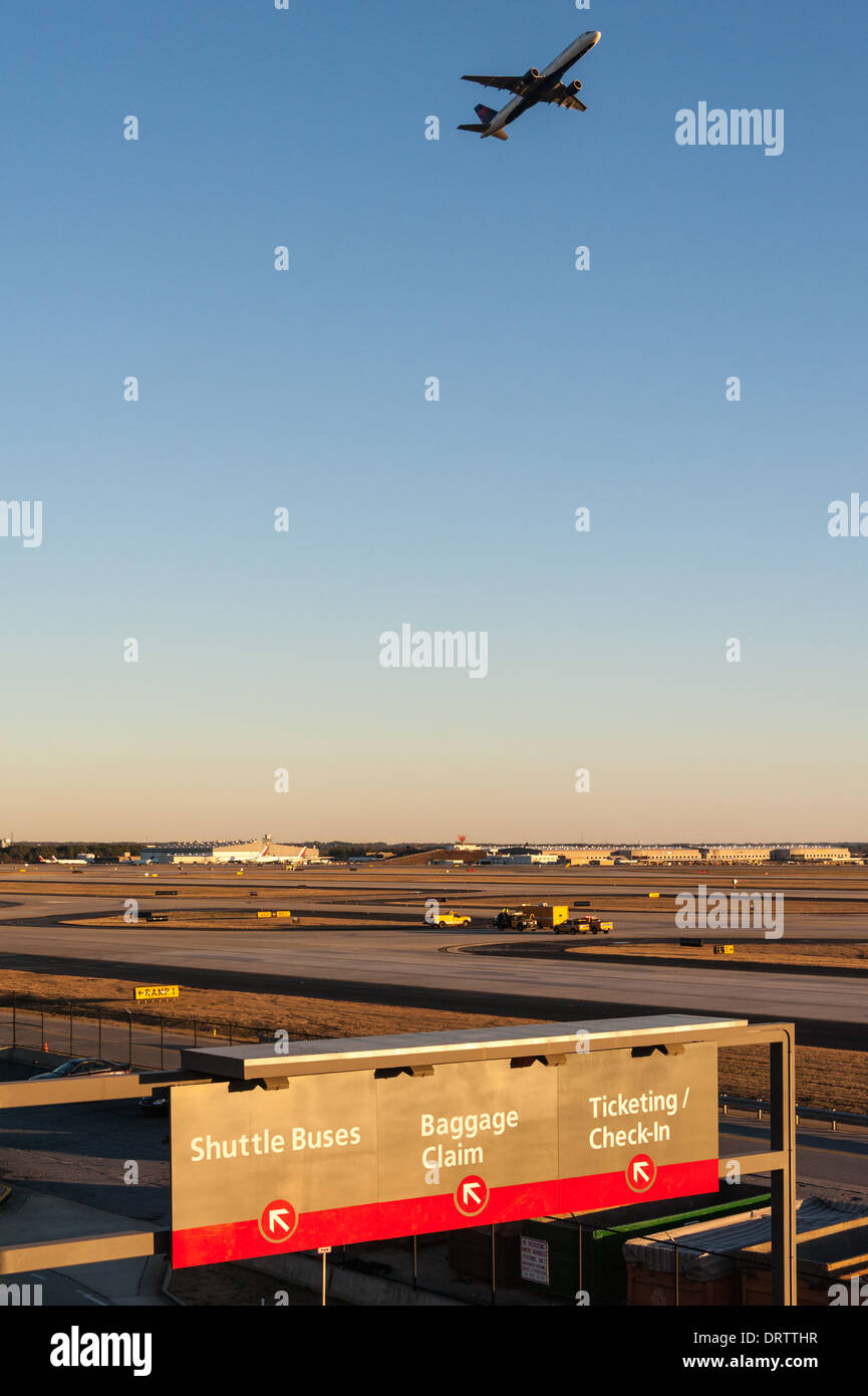 Il tramonto illumina la segnaletica direzionale mentre un jet passeggeri si solleva all'aeroporto internazionale di Atlanta ad Atlanta, Georgia. (USA) Foto Stock