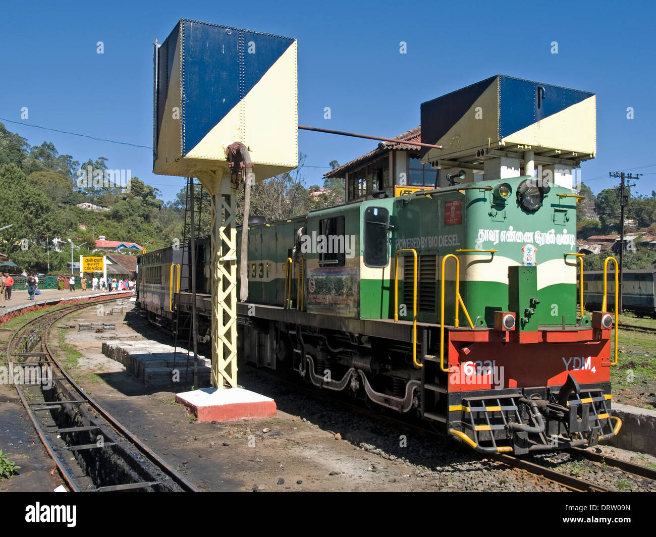 Un verde-powered locomotiva diesel attende accanto alle torri d'acqua a Coonoor stazione sul patrimonio della linea ferroviaria fino a Ooty. Foto Stock