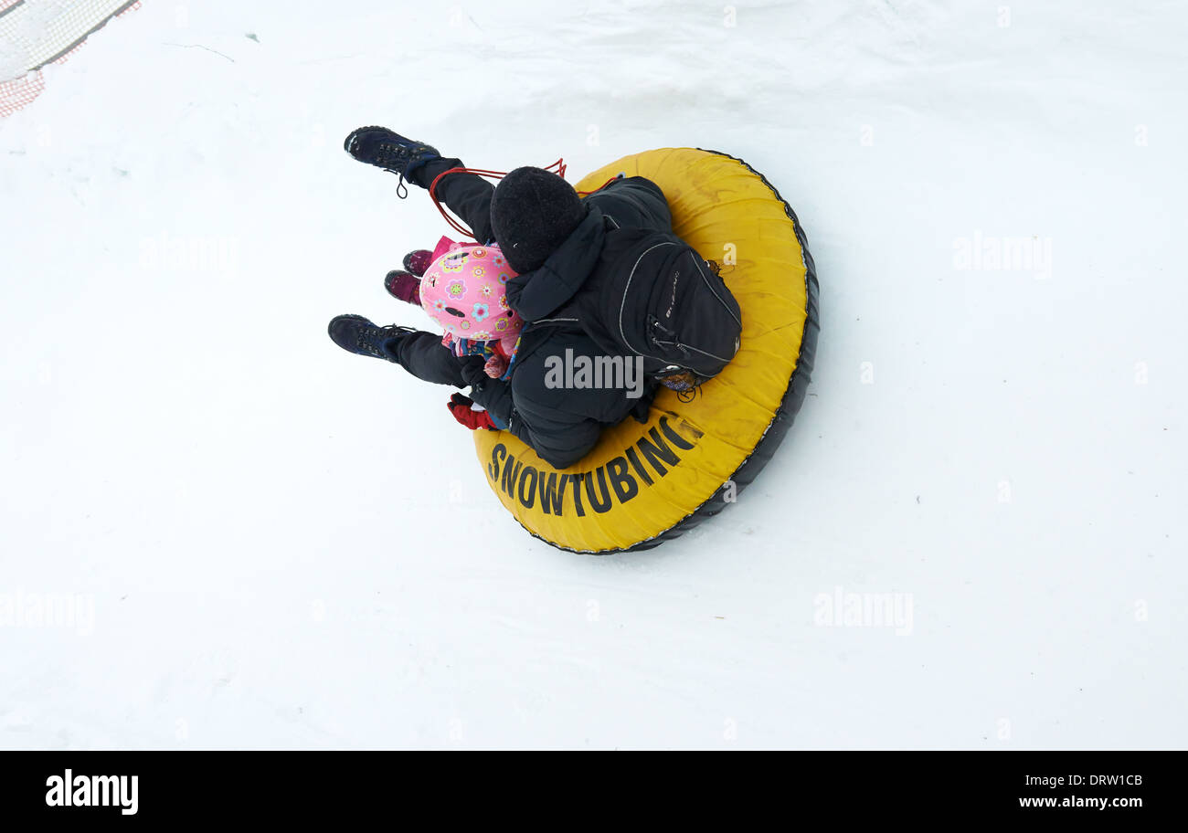 Padre e figlia avendo divertimento nella neve tubo interno - snowtubing Foto Stock
