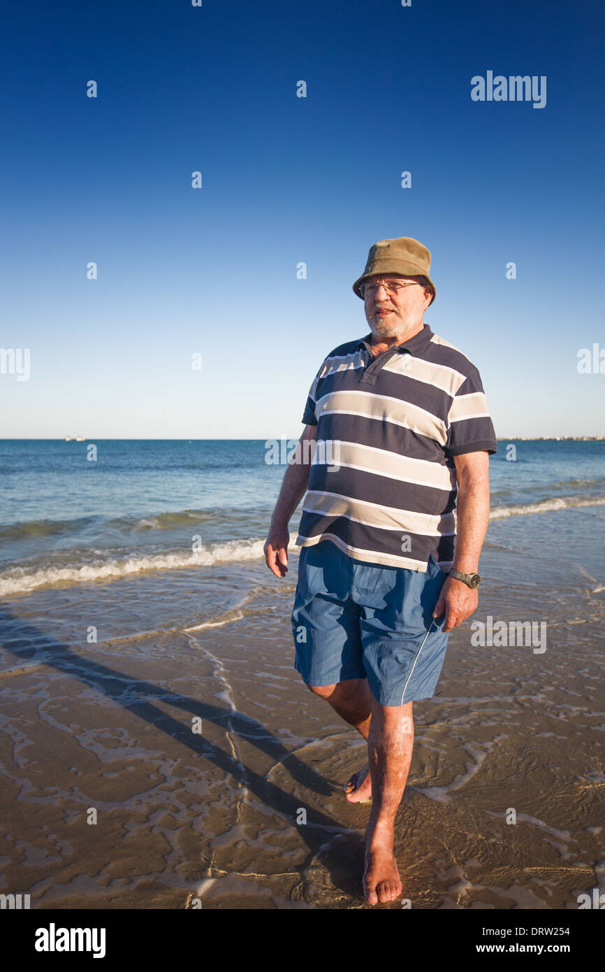 Senior uomo a camminare sulla spiaggia Foto Stock