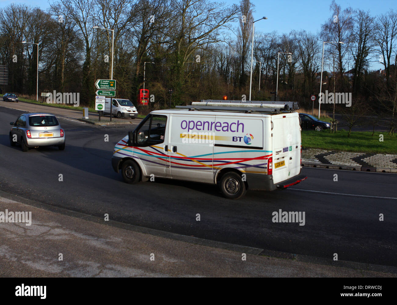 Un BT Openreach van e di un automobile che viaggia intorno ad una rotonda a Coulsdon, Surrey, Inghilterra Foto Stock