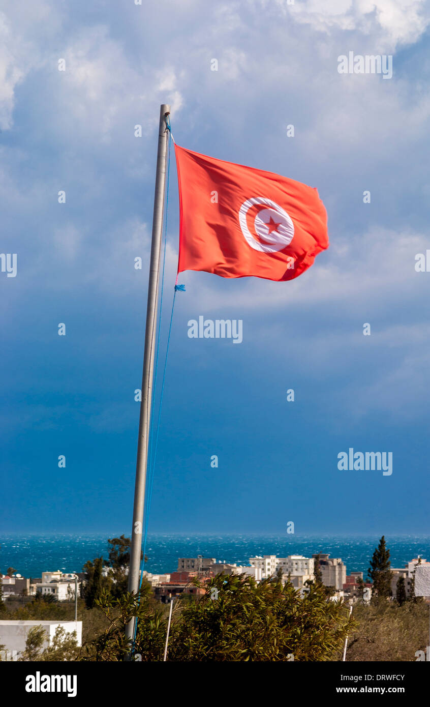 Bandiera tunisina con edifici e mare in background Foto Stock