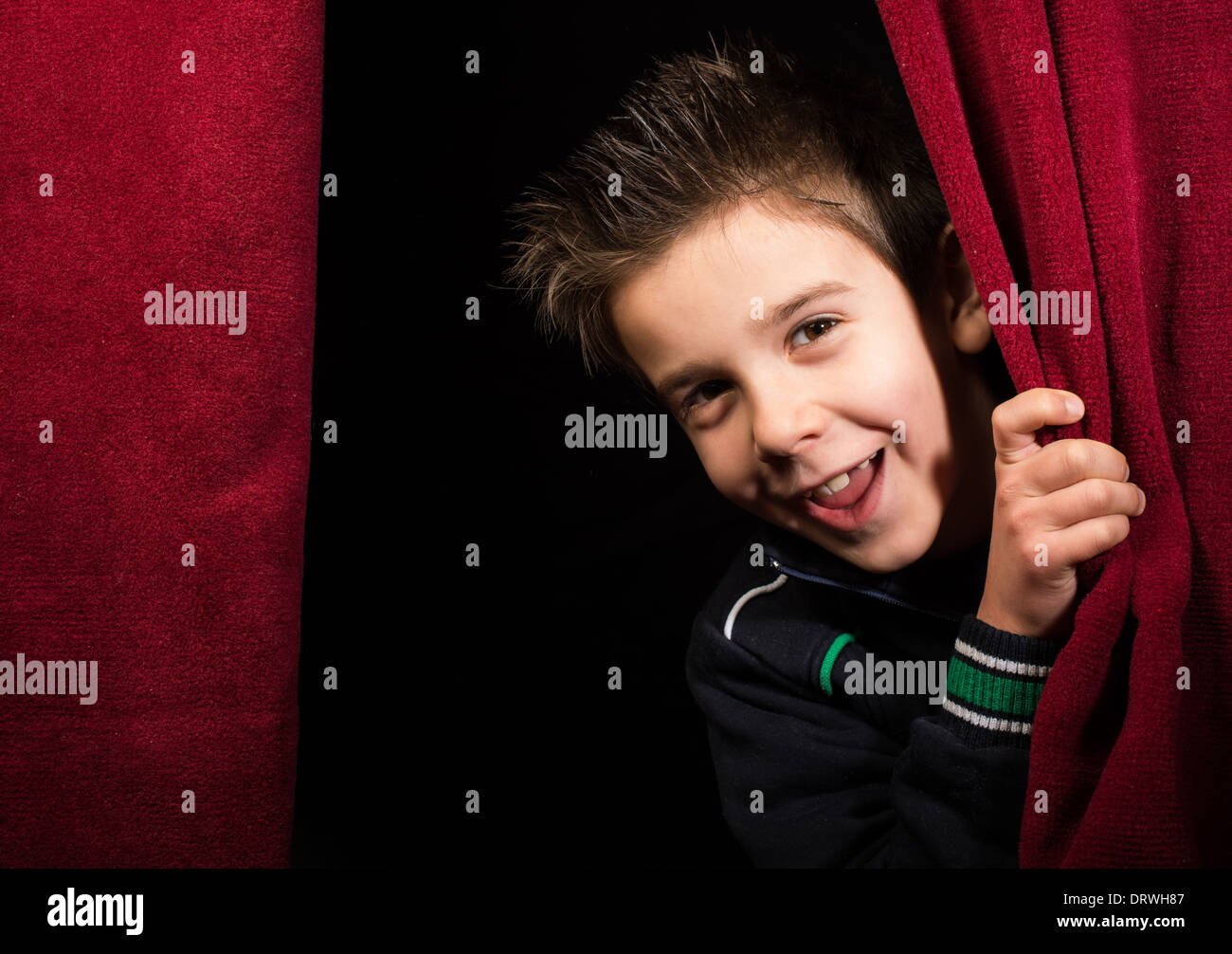 Bambino che figurano sotto la tenda. Sipario rosso. Foto Stock