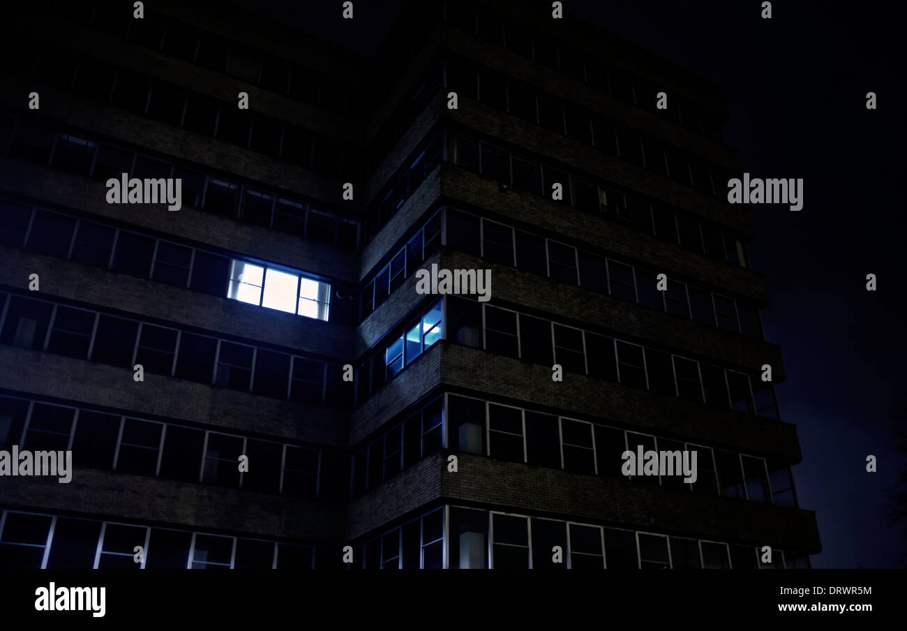 Edificio per uffici di notte con solo una finestra illuminata Foto Stock