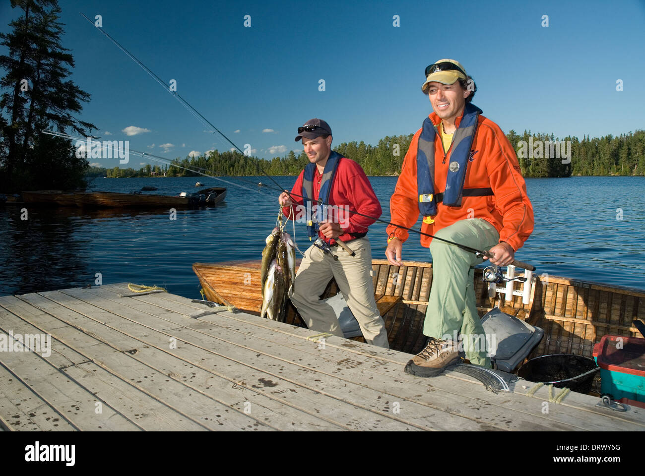 Gli amici di pesca di salire sulla dock dopo una giornata di pesca walleye d'estate. Foto Stock