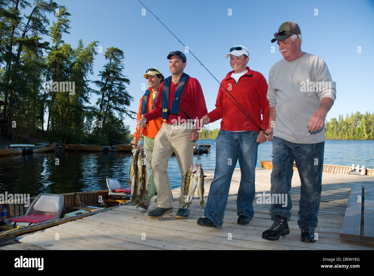 Gli amici di pesca di salire sulla dock dopo una giornata di pesca walleye d'estate. Foto Stock