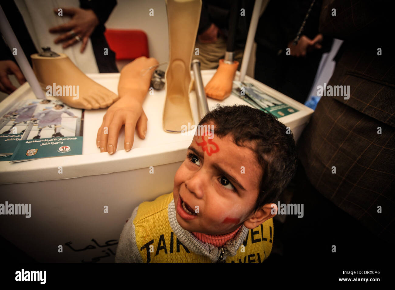 La striscia di Gaza City, nella Striscia di Gaza . 3 febbraio, 2014. Un giovane ragazzo sta in piedi di fronte ad una vetrina contenente varie arti protesici come Palestinesi prendere parte a una manifestazione di protesta di fronte all'ufficio della Croce Rossa per chiedere il rilascio di parenti detenuti come prigionieri nelle carceri israeliane. Credito: Momen Faiz/NurPhoto/ZUMAPRESS.com/Alamy Live News Foto Stock