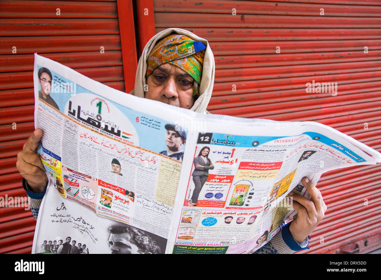 Uomo musulmano la lettura di un quotidiano nella Vecchia Delhi, India Foto Stock