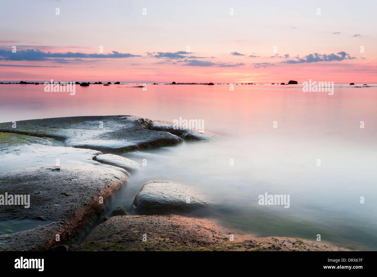 Tramonto al mare dietro costa rocciosa in estate Foto Stock