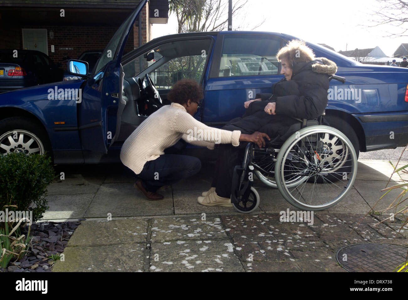 Regno Unito west sussex una donna anziana essendo aiutato dal caregiver ad entrare in una macchina Foto Stock