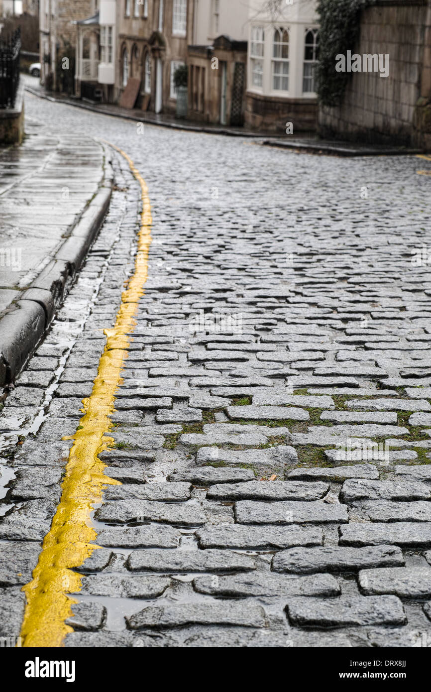 Linea gialla singola su una strada acciottolata Foto Stock