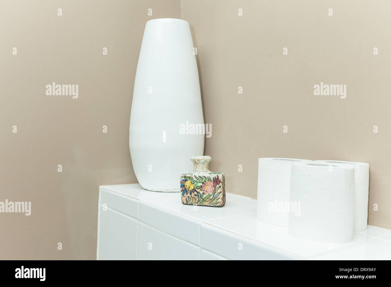 Fiore bianco vaso e rotoli di carta igienica sul cabinet bianco. Foto Stock