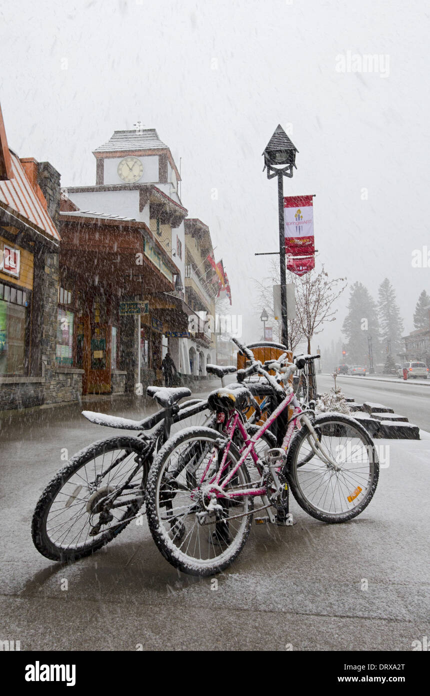 Coperta di neve bici durante una raffica di neve nella strada principale di Banff, Alberta, Canada Foto Stock