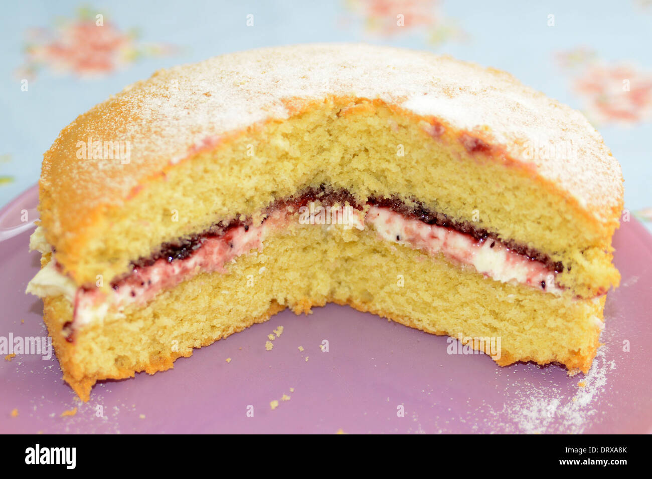 In casa Victoria sponge cake su una piastra di rosa Foto Stock