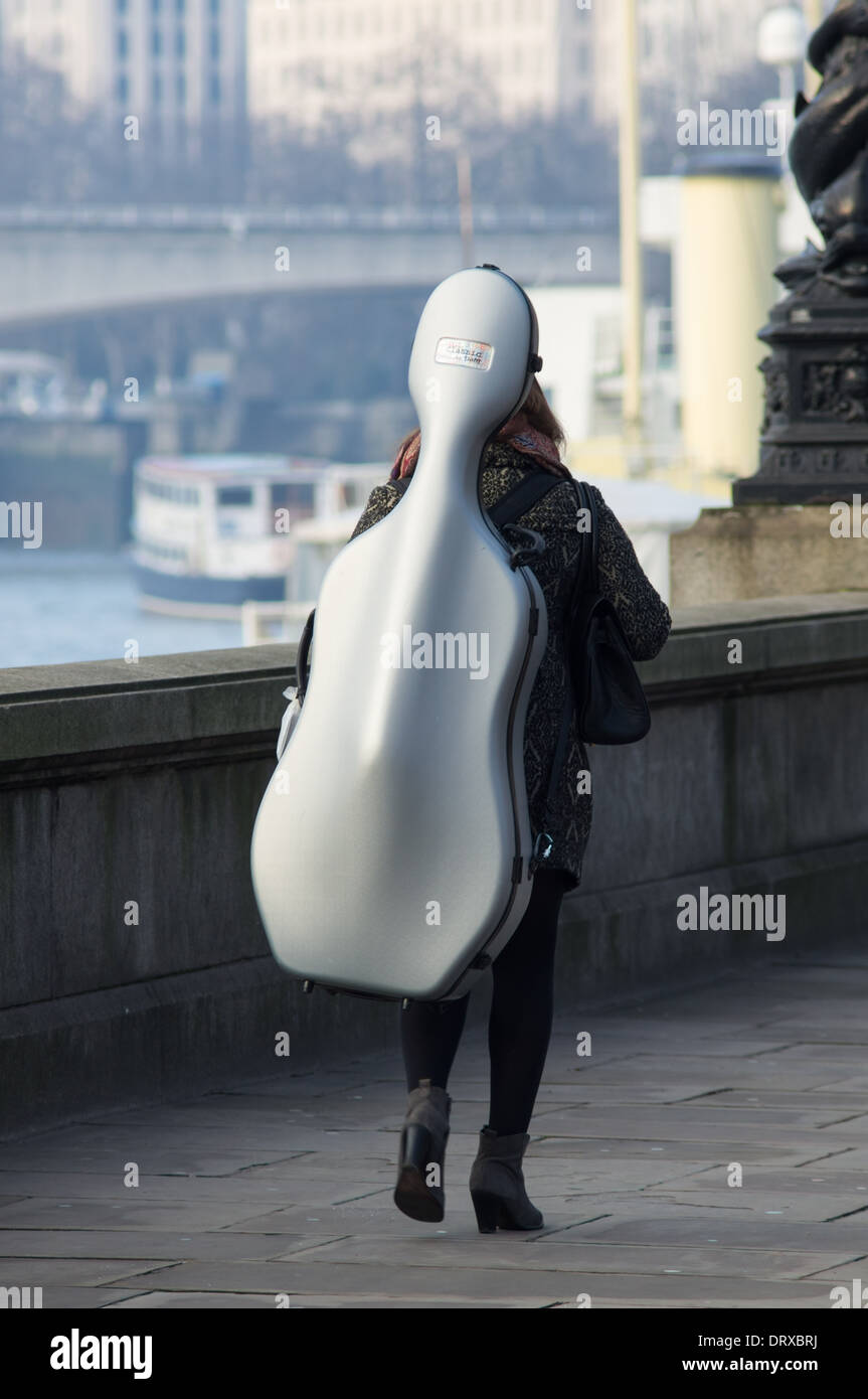 Donna che trasportano violoncello sul Tamigi riverbank, Londra England Regno Unito Regno Unito Foto Stock