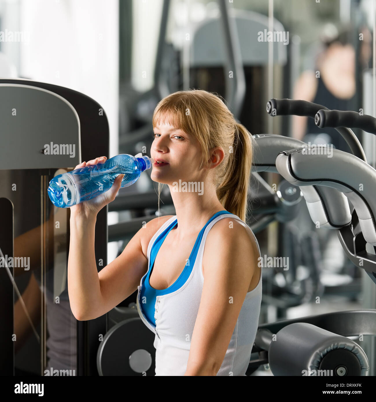 Donna bere acqua a macchina fitness Foto Stock