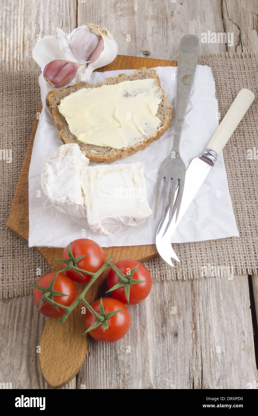 Tavola di legno con formaggio di capra, pane e pomodoro Foto Stock