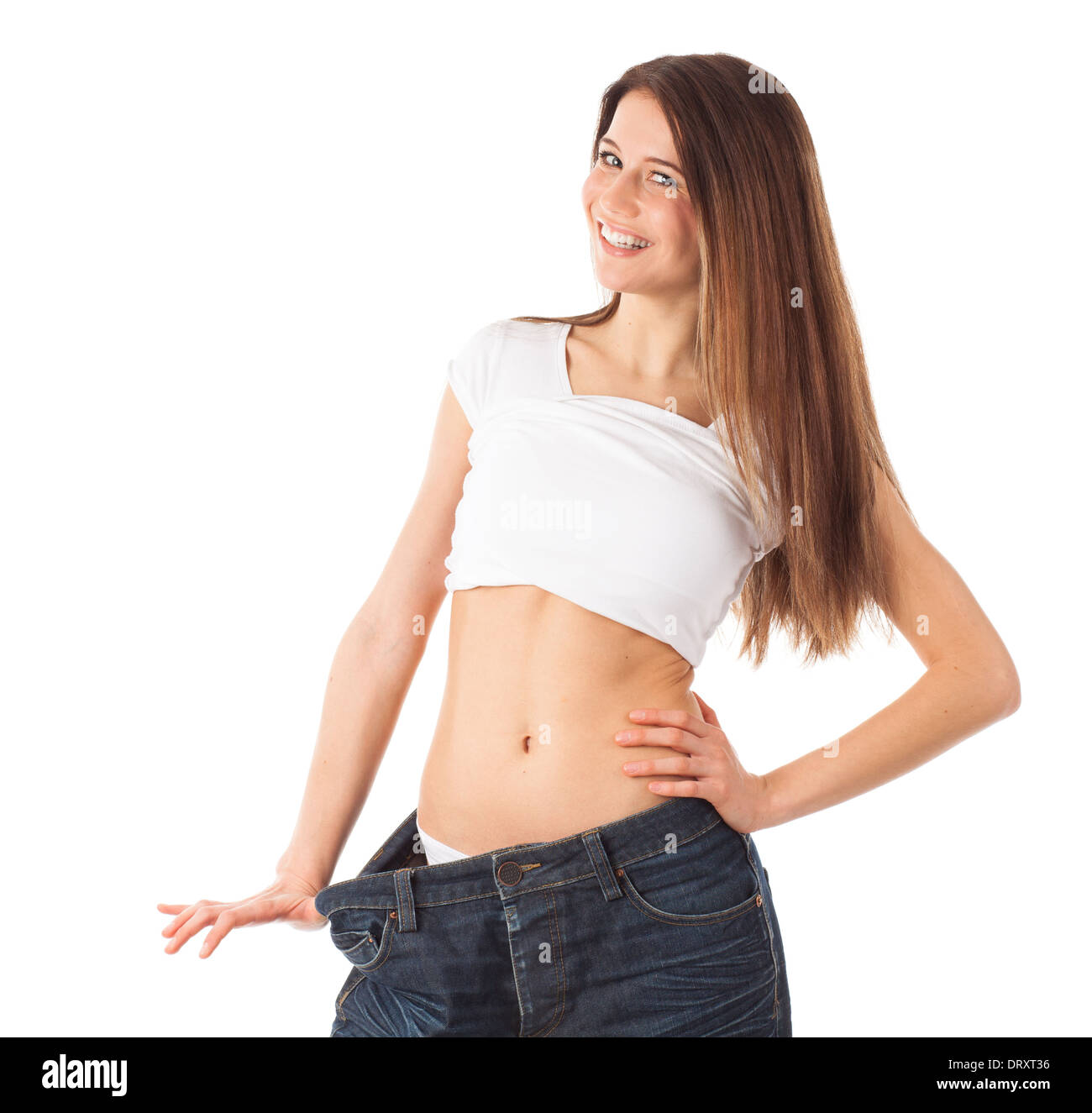 Allegro giovane donna che mostra la sua vita indossando un vecchio jeans, isolato su bianco Foto Stock