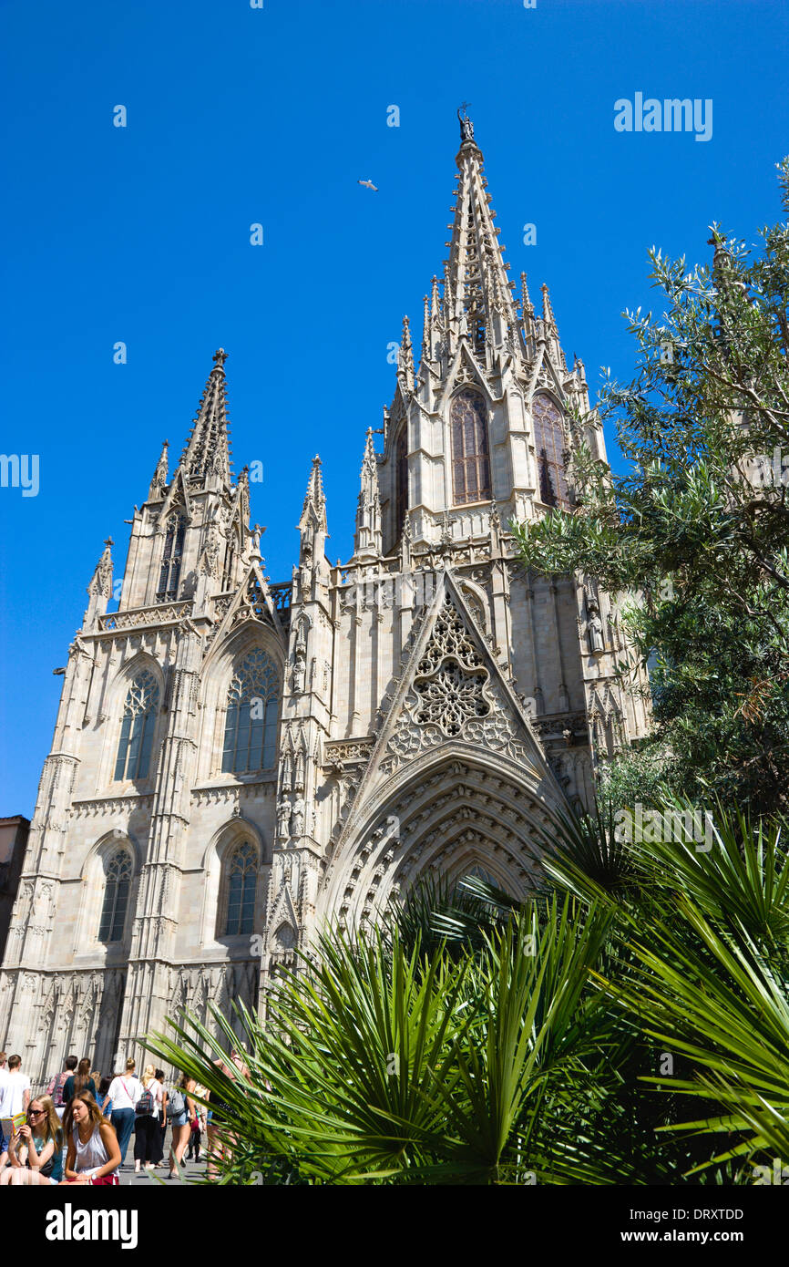In Spagna, in Catalogna, Barcellona, persone su i passi al di sotto della facciata principale e la guglia della cattedrale gotica. Foto Stock