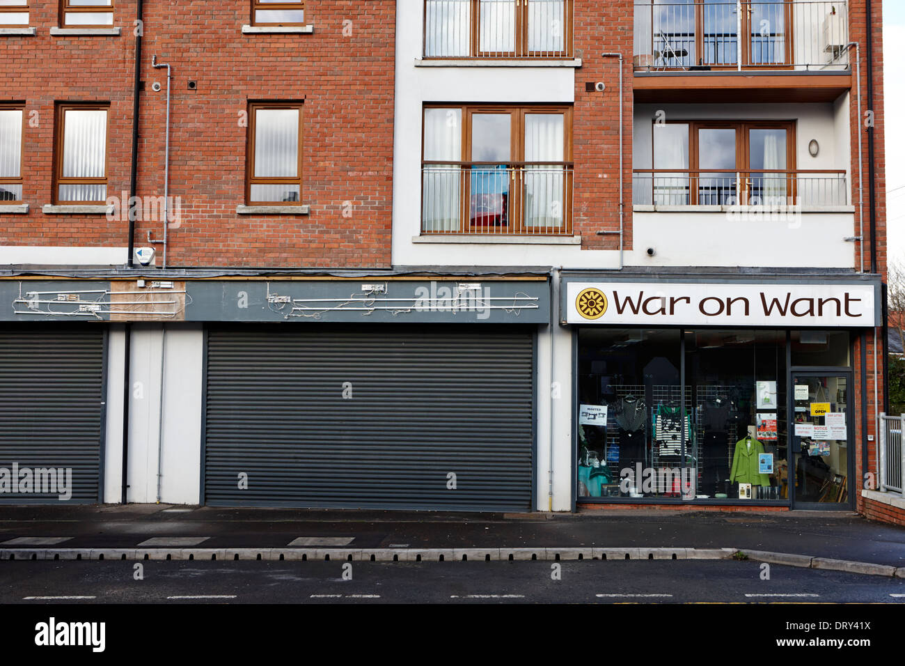 War on Want carità shop accanto al negozio chiuso su high street dunmurry Belfast Regno Unito Foto Stock
