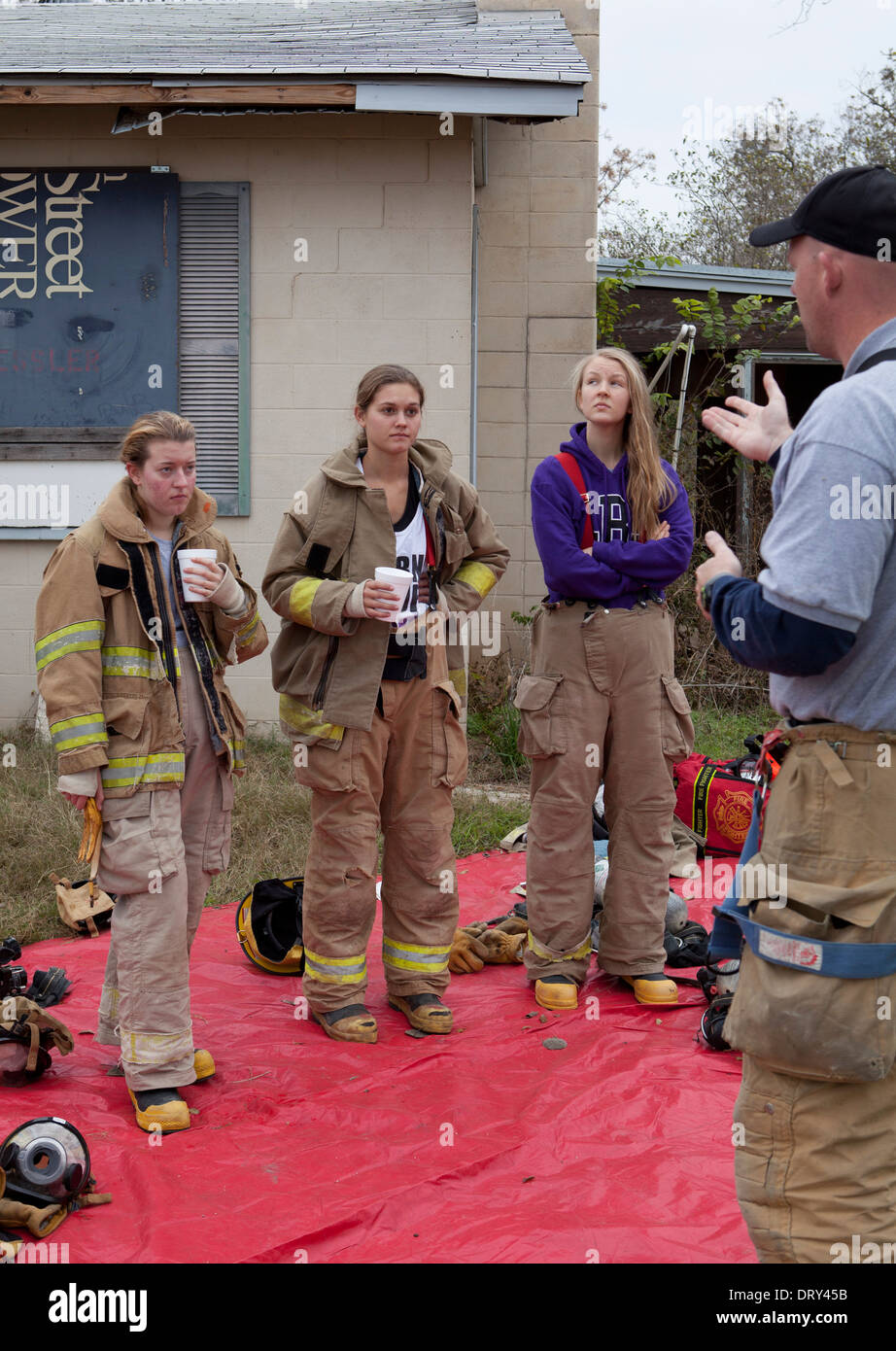 Donne studenti dalla scuola di alta formazione antincendio classe ascoltare istruttore prima esercitazione in casa abbandonata Foto Stock