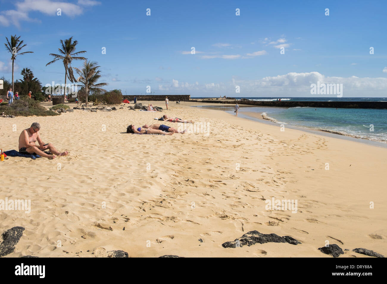 La gente a prendere il sole sulla spiaggia sabbiosa di Playa de Las Cucharas beach in Costa Teguise, Lanzarote, Isole Canarie, Spagna, Europa. Foto Stock