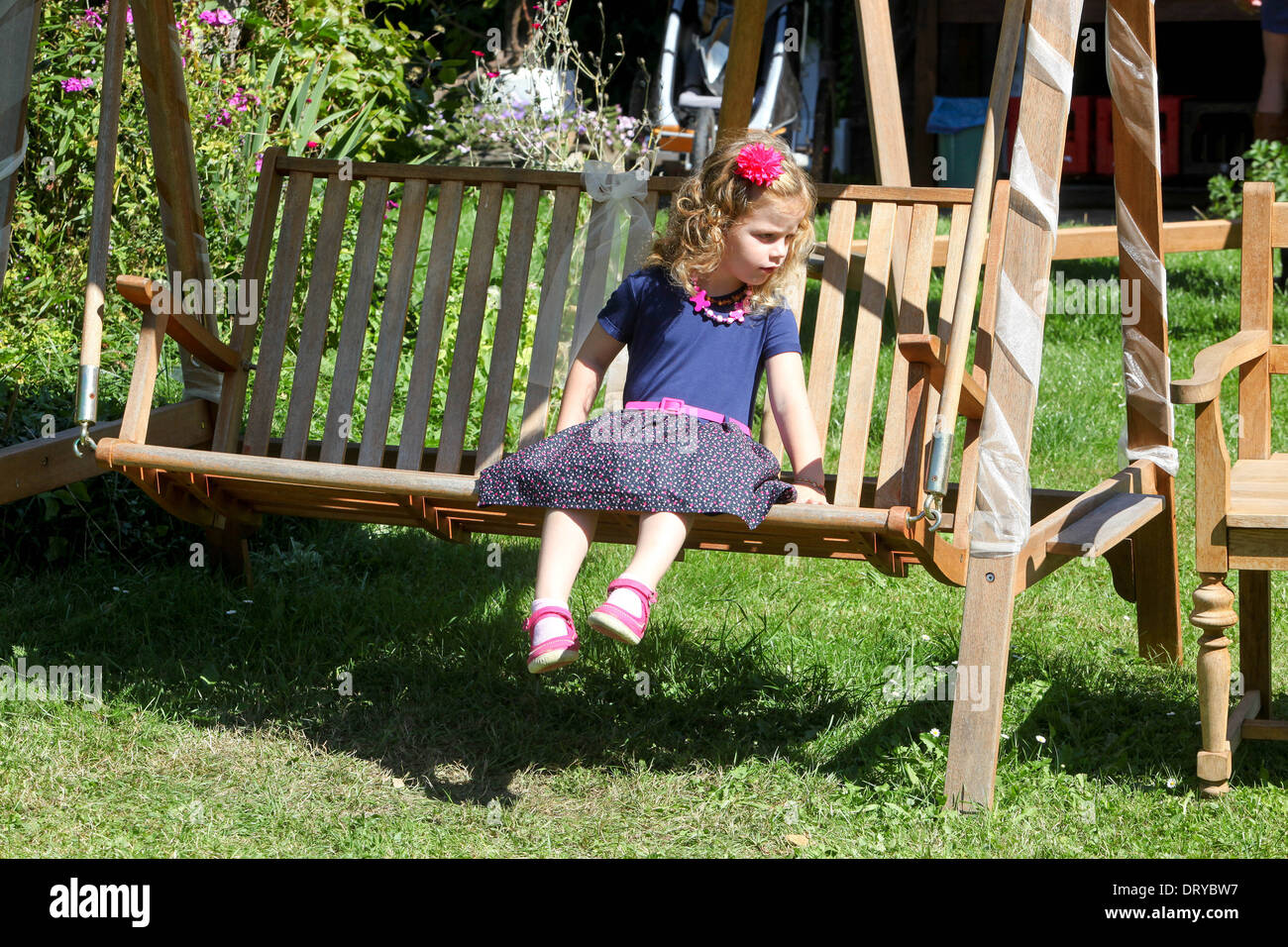 Ragazza lttle su un giardino di legno swing sedile bambino su portico swing Foto Stock
