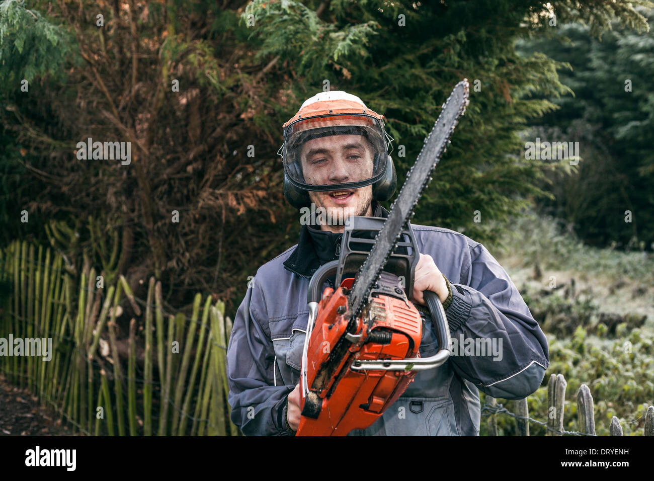 Ritratto di professionale giardiniere con chainsaw in piedi nel giardino. Foto Stock