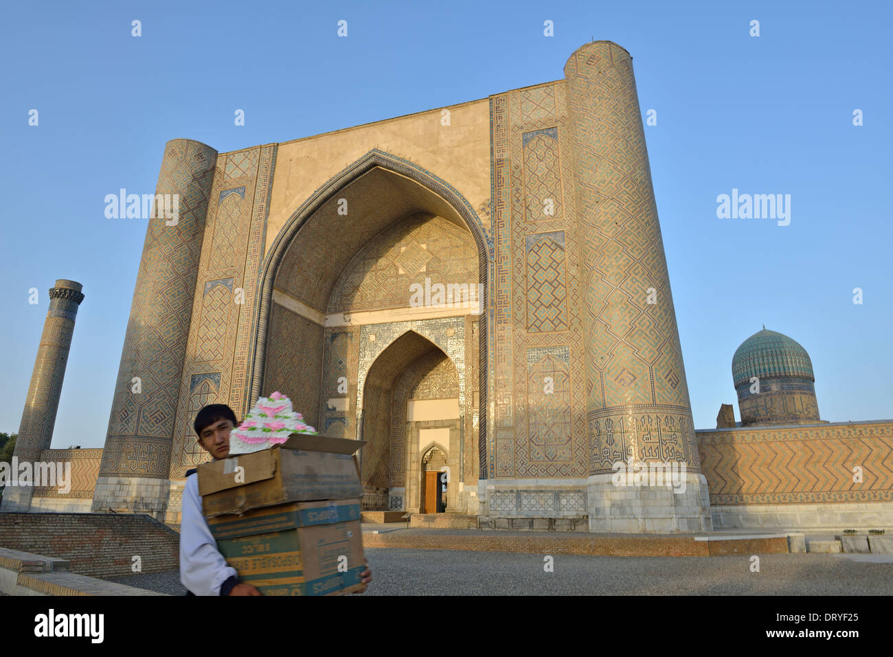 Uomo che porta una torta al mercato Siyob con Bibi-Khanym moschea in background, Samarcanda, Uzbekistan Foto Stock