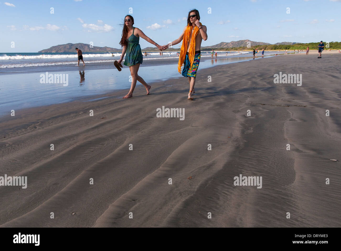 Un giovane Costa Rican giovane tenendo le mani a piedi verso il basso sulla spiaggia a Playa Tamarindo, Guanacaste in Costa Rica Foto Stock
