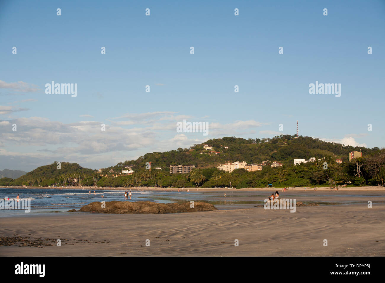 Una vista lungo la spiaggia e la città con le colline alle spalle di Playa Tamarindo, Guanacaste in Costa Rica Foto Stock