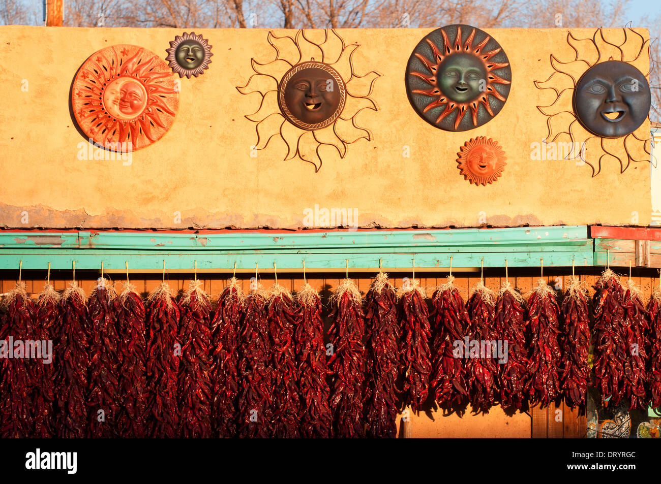 Peperoni secchi e arte esposte contro una struttura di adobe accesa dal tardo pomeriggio sun. Foto Stock