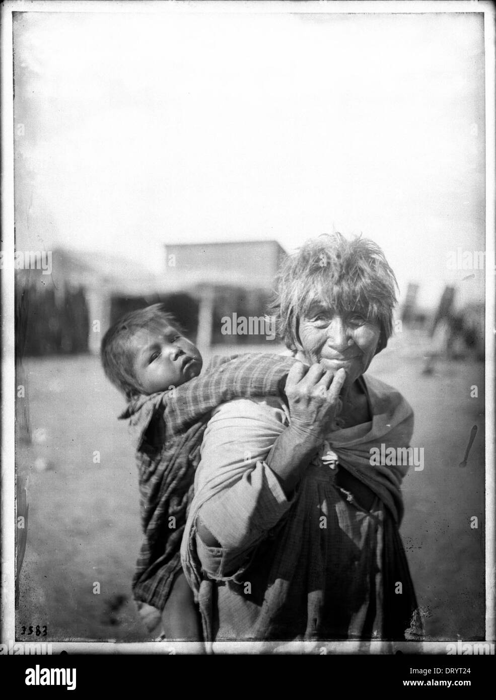 Una fotografia di una nonna indiana Apache che porta suo nipote sulla schiena nella riserva indiana Palomas intorno al 1900, che riflette la vita familiare indigena. Foto Stock